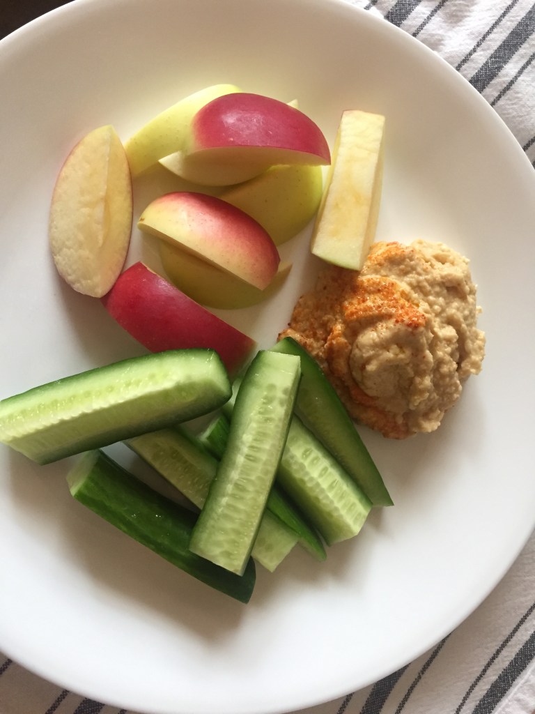 Hummus made by Homemade In LA alongside sliced apples and cucumbers.